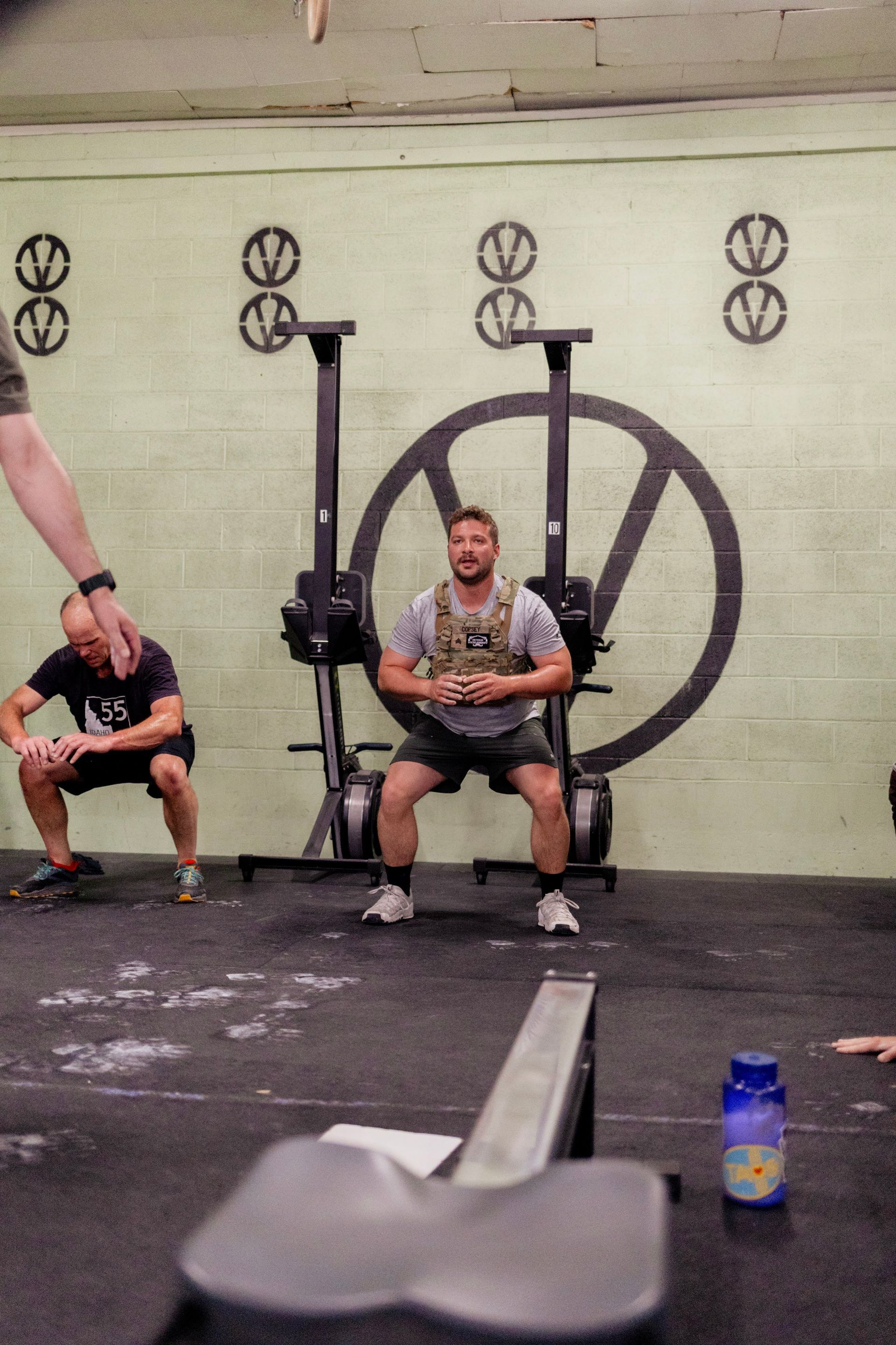 Man squats with weight vest in a Boise gym, surrounded by others working out.