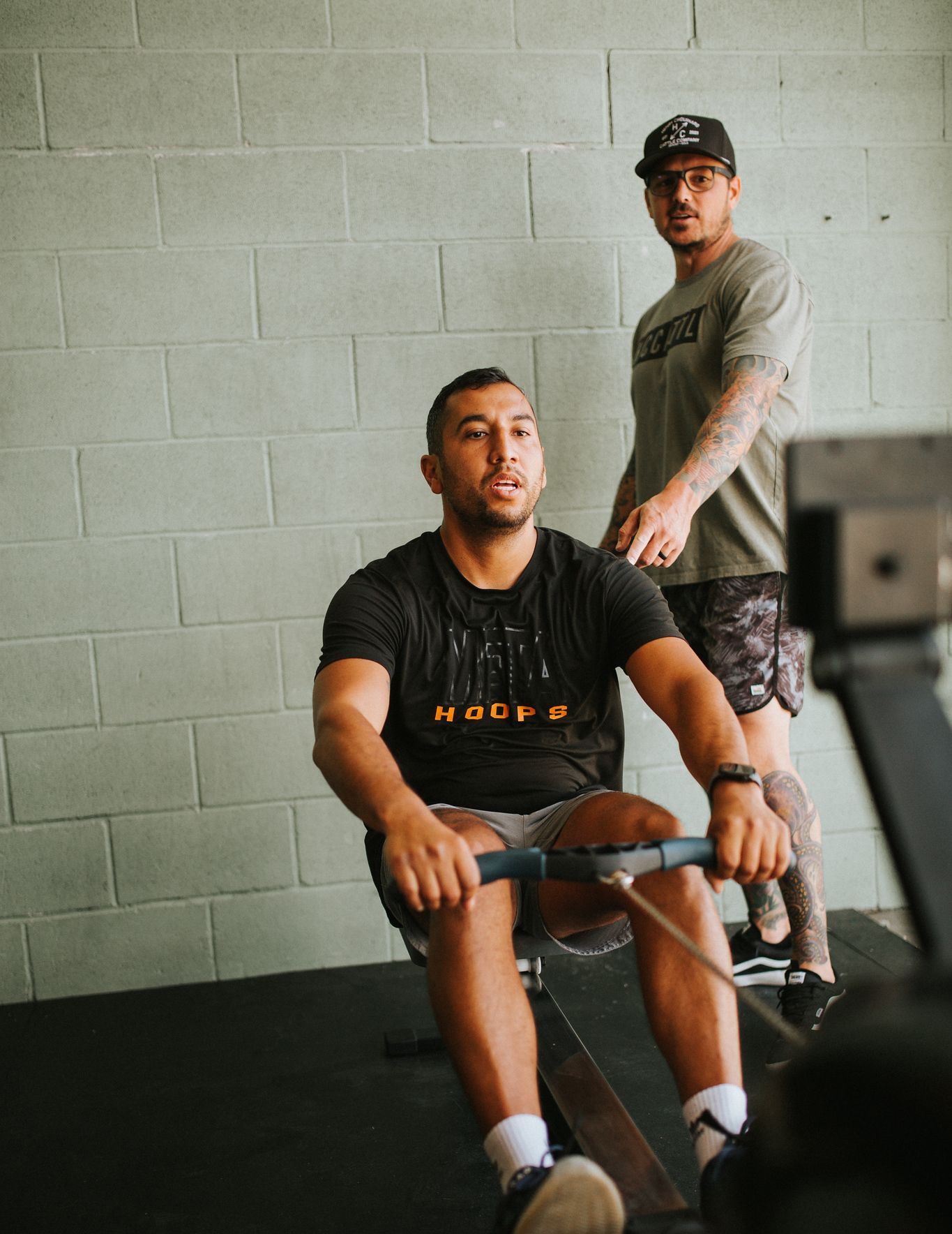 Man rowing with trainer in a gym in Star, ID. Man is sweating and focused. Trainer looks on with a serious expression.