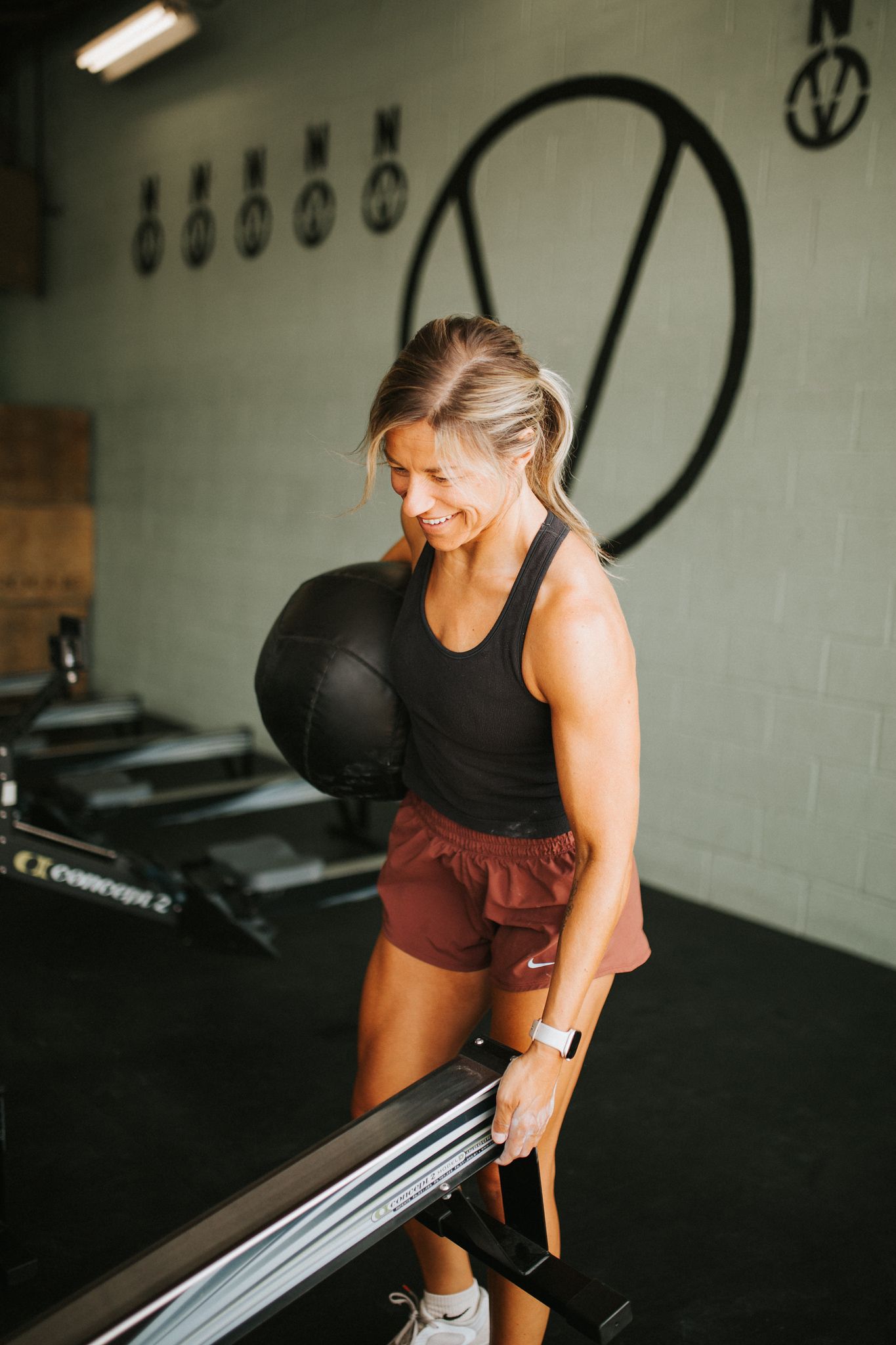 Woman at Verdant CrossFit in Star, ID holding medicine ball and equipment, smiling.