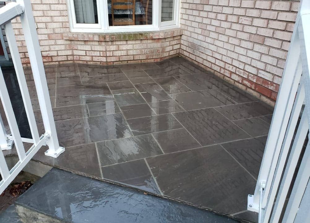Wet concrete pouring from a truck chute onto a construction site, forming a gravelly slab surface