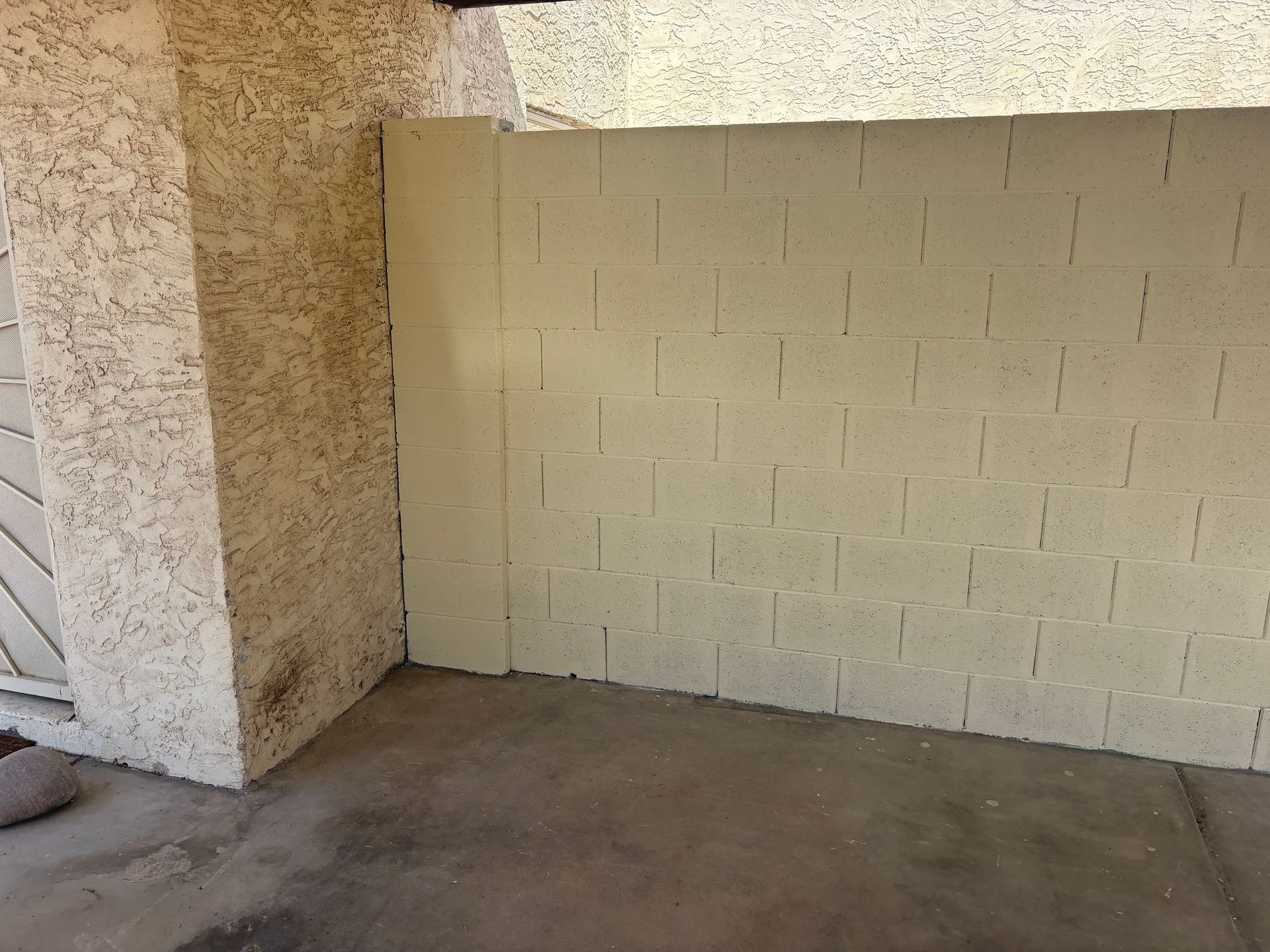Empty beige brick wall beside a concrete pillar on a covered walkway