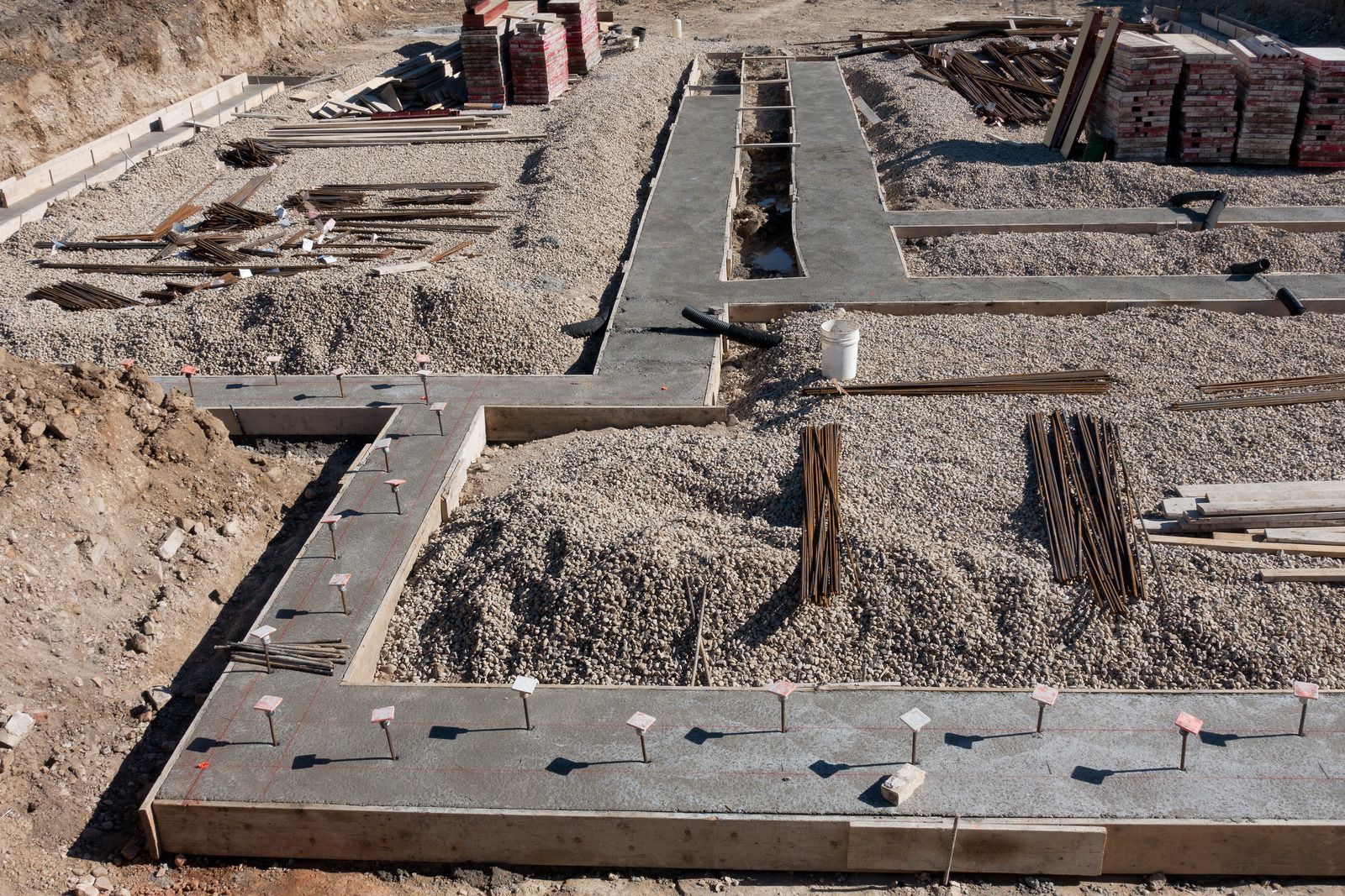 Construction workers pouring concrete at a building site, with a truck in the background