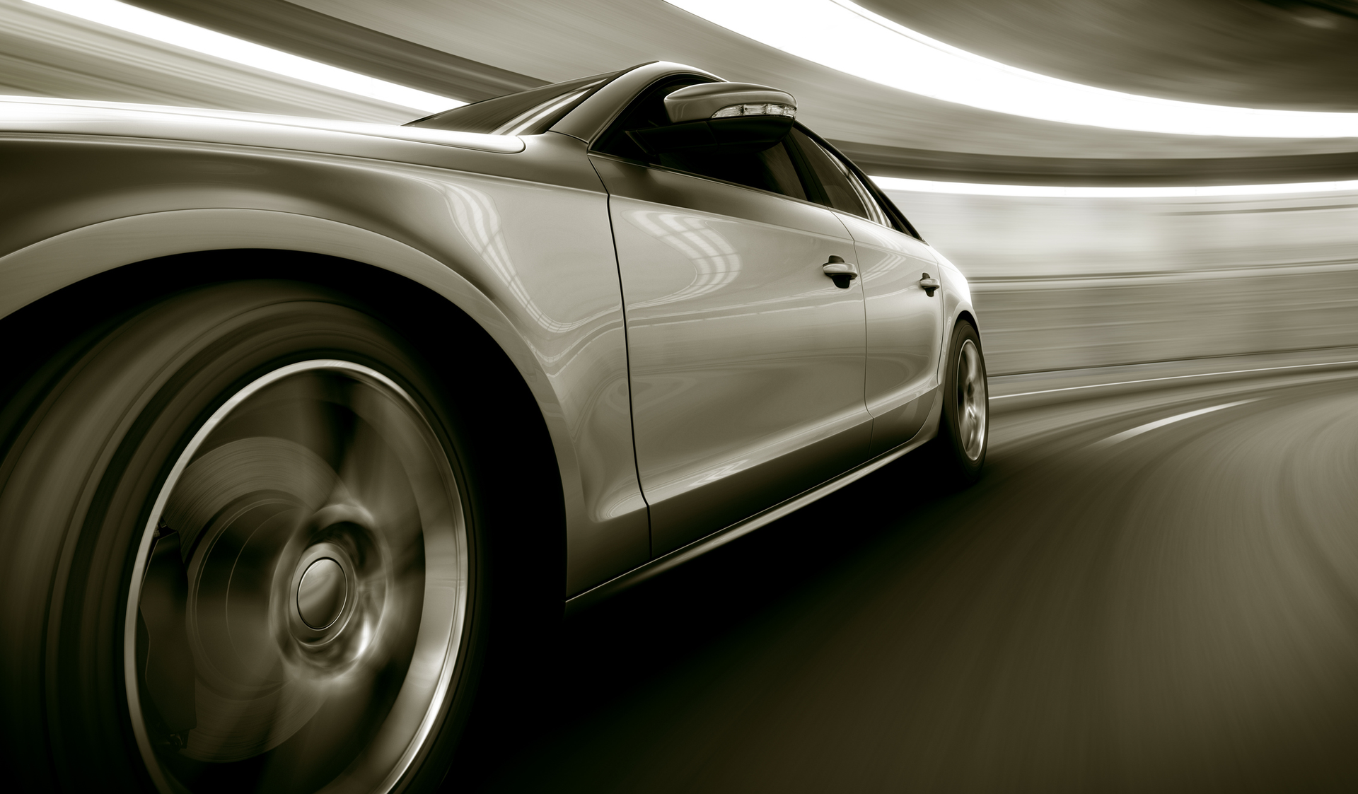 A sleek, silver car speeding around a curve, blurring motion against a dark, tunnel-like background.