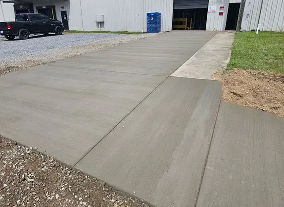 A black truck is parked on the side of a concrete driveway.
