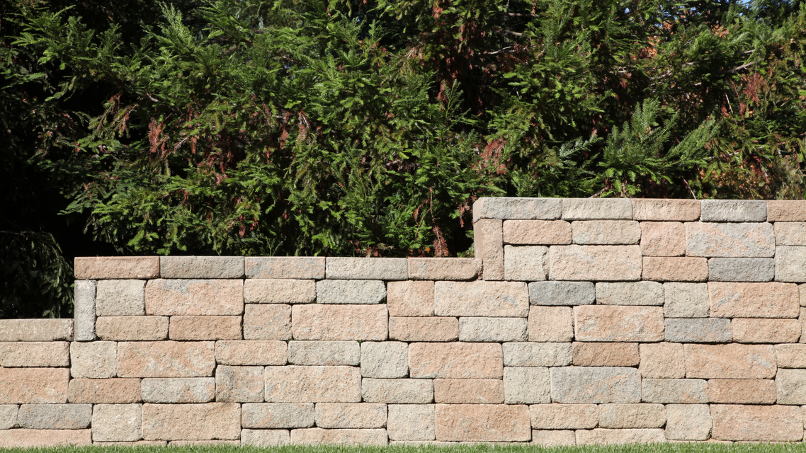 A brick wall is surrounded by trees in a backyard.