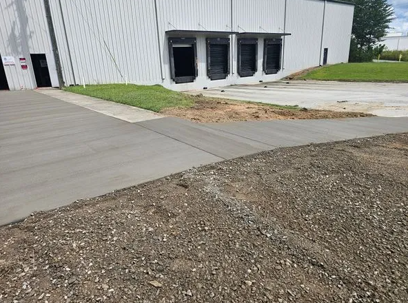 A concrete driveway is being built in front of a large white building.