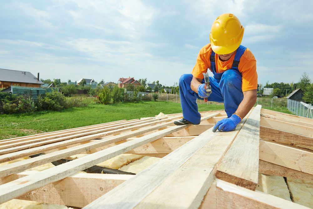 Construction Worker in a Yellow Hard Hat on a Wooden Roof, Hammering — CJ Custom Carpentry in Kempsey, NSW