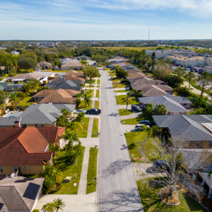 Aerial view of a suburban street lined with single-family homes and palm trees under a clear sky