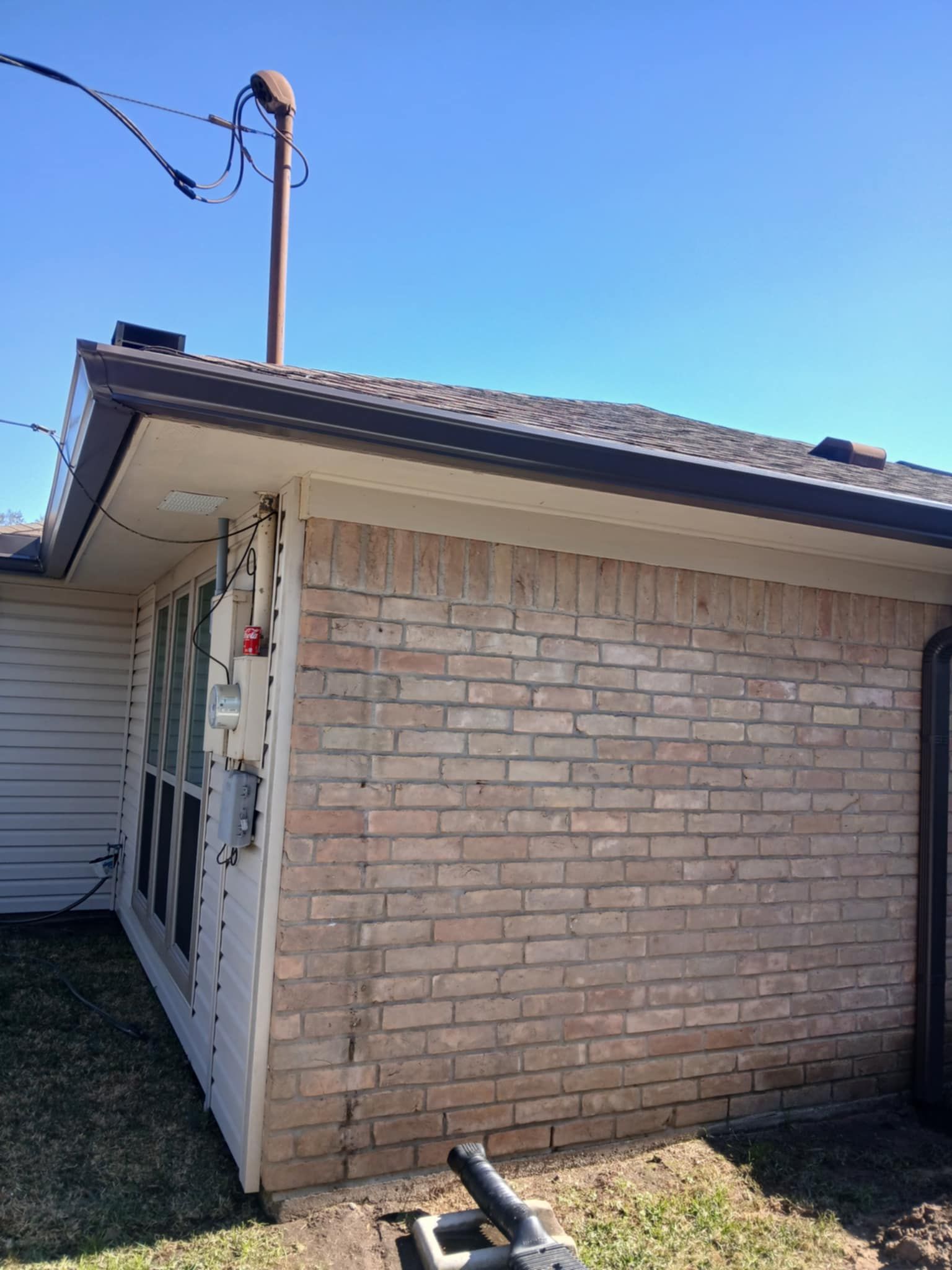 Brick building exterior with a brown roof and utility pole against a blue sky.