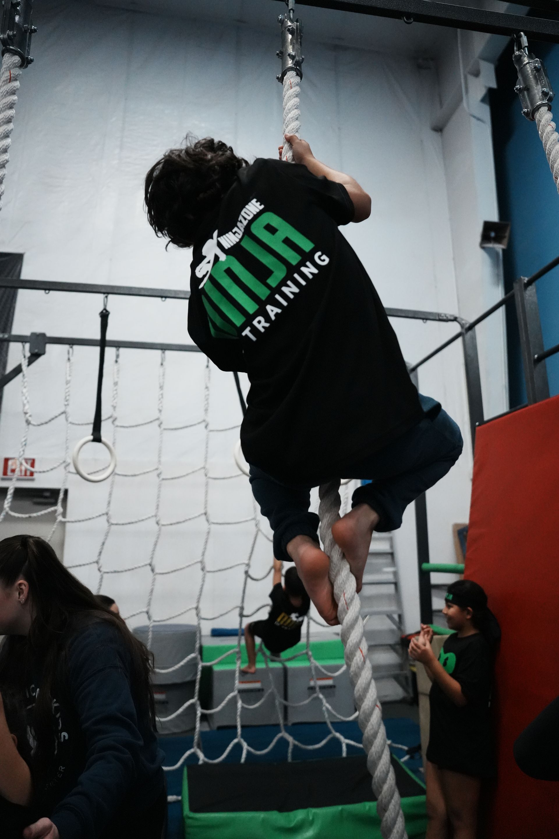Ninja Coach helping athlete up warp wall.