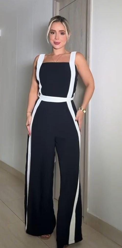 Mujer con un mono blanco y negro, de pie en una puerta.