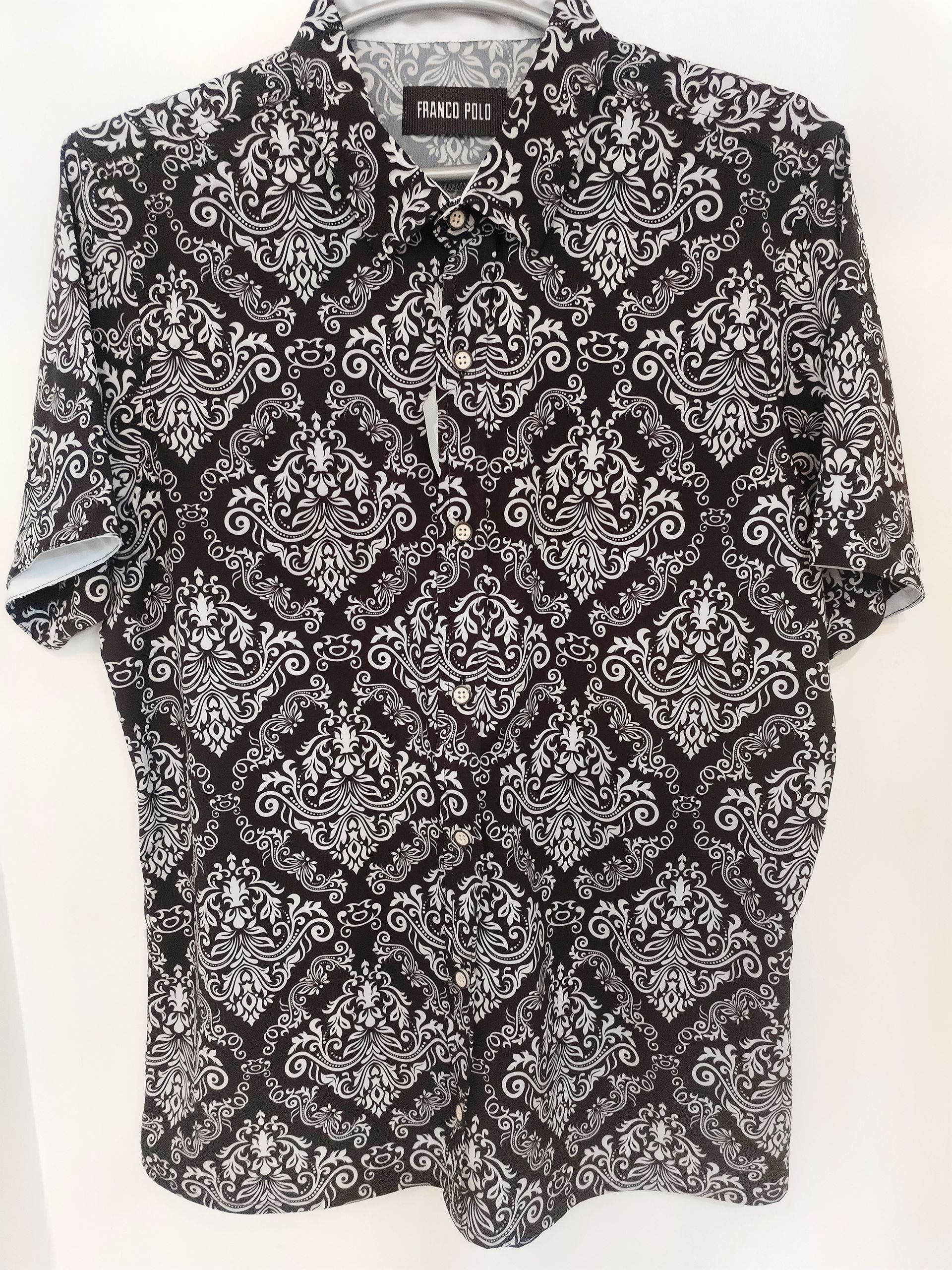 Camisa de manga corta con botones y mangas dobladas, estampada en blanco y negro.