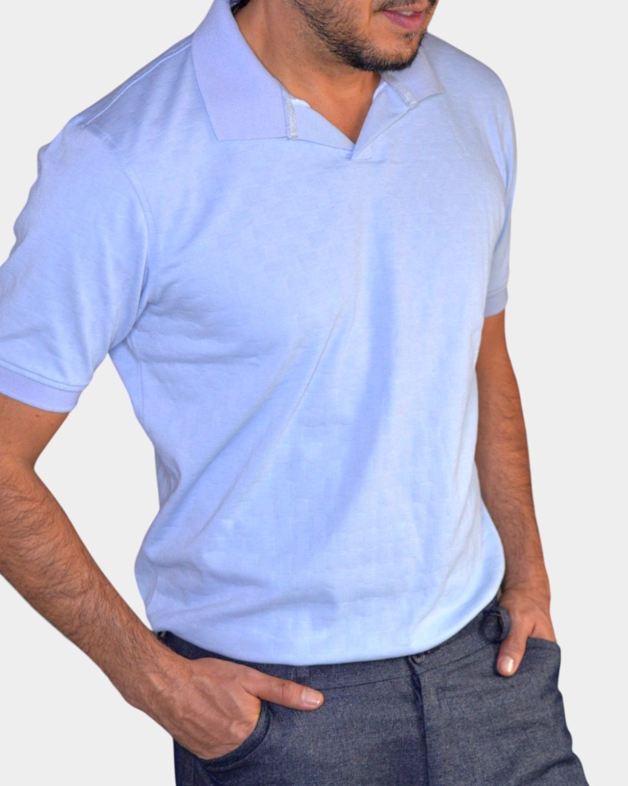 Hombre con un polo azul claro y las manos en los bolsillos.
