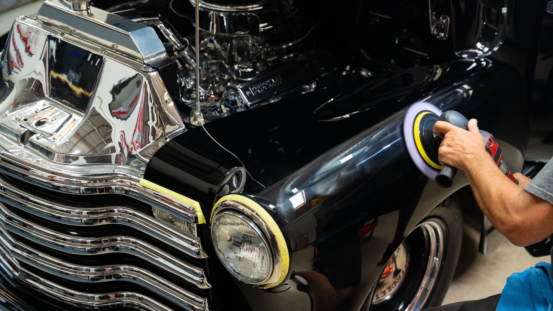 a man is polishing the front of a black car
