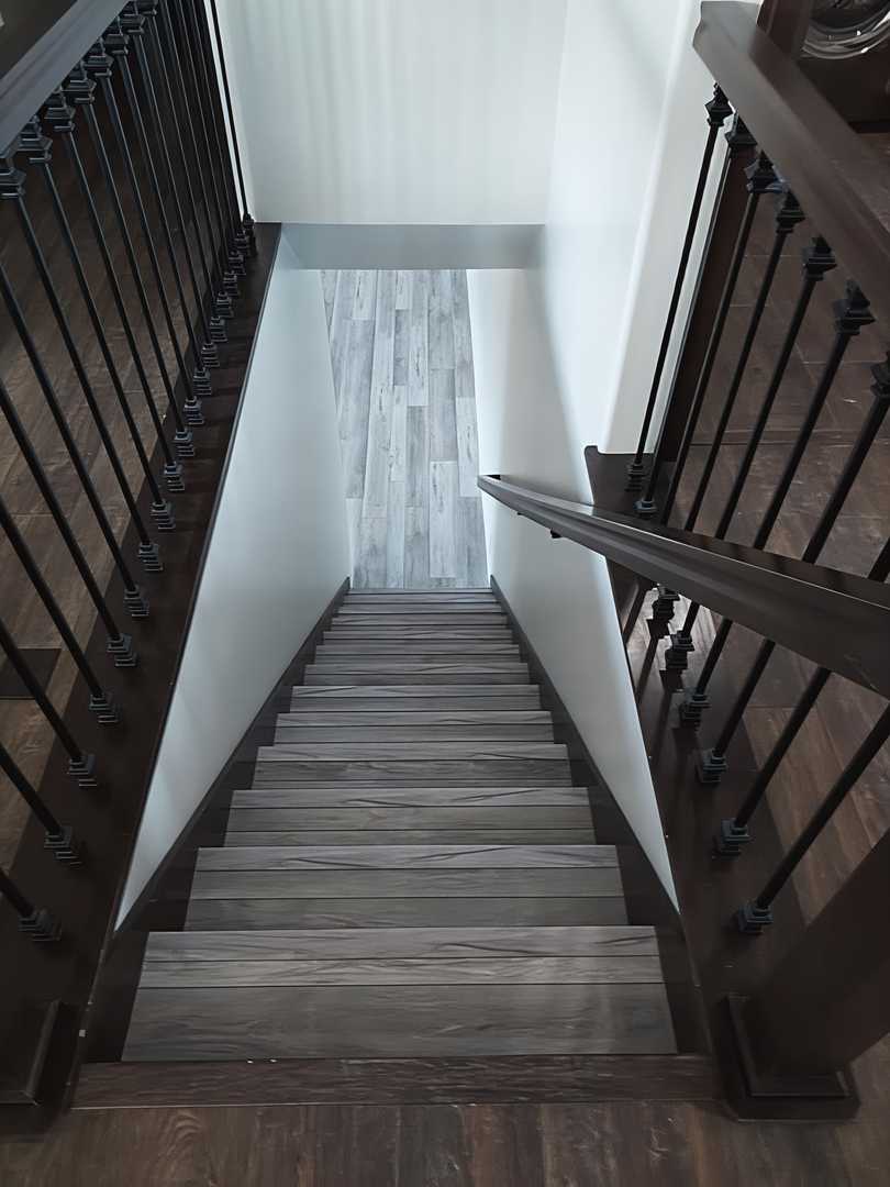 Steep wooden staircase with dark railings leading down to a bright hallway.