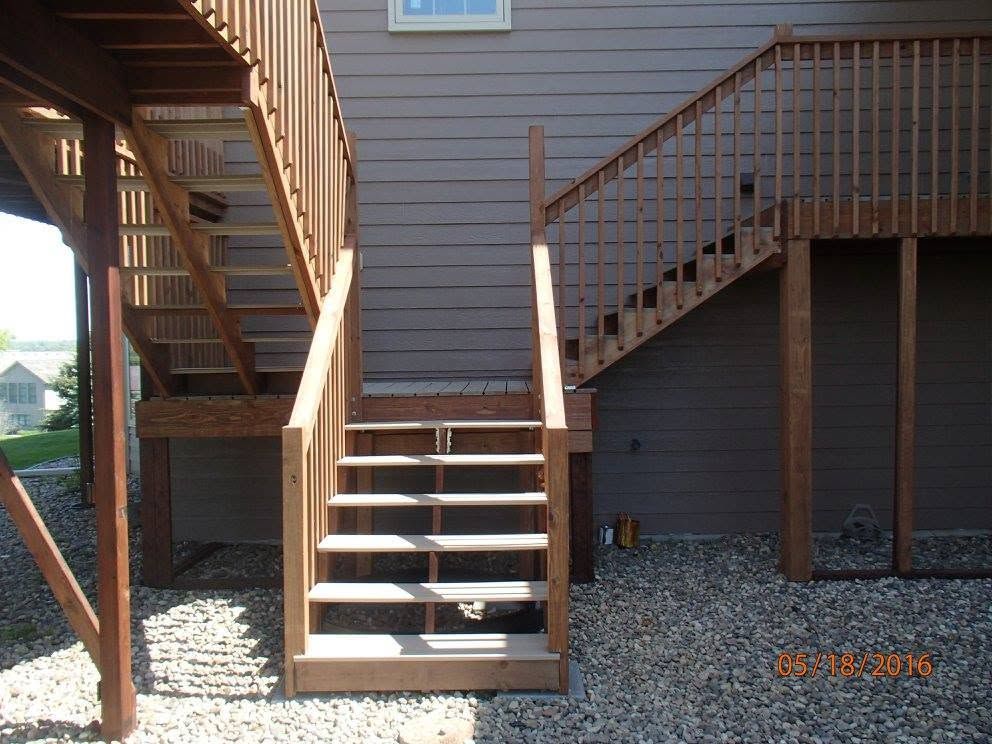 Backyard exterior stairways with wooden railings and gravel underneath the deck