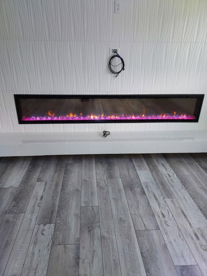 Modern wall-mounted electric fireplace with purple flames beneath a TV mount in a room with gray flooring