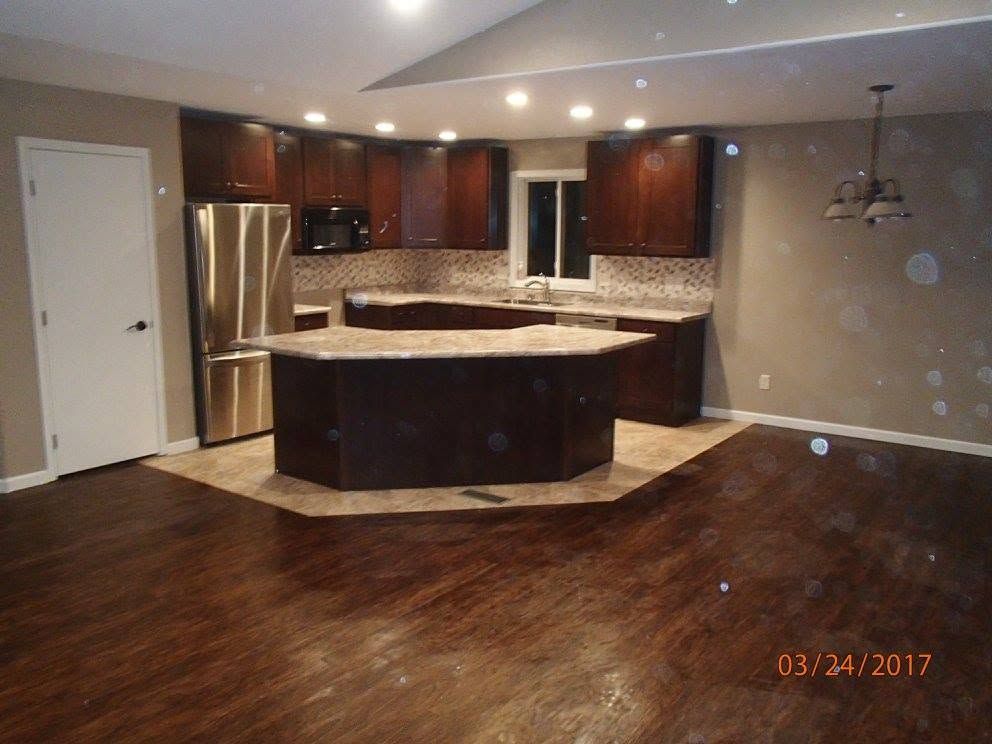 Modern kitchen with dark wood cabinets, stainless fridge, large island, and hardwood floors