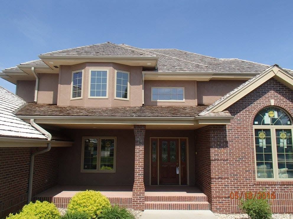 Two-story brick suburban house with a covered front porch and arched window details