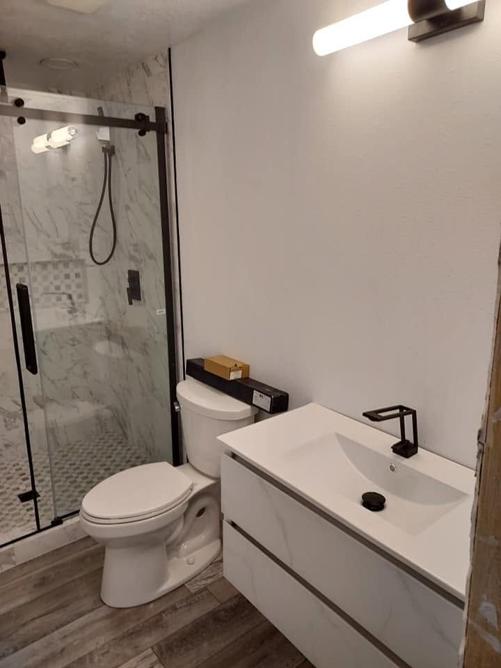 Modern bathroom with glass shower, toilet, and white vanity sink