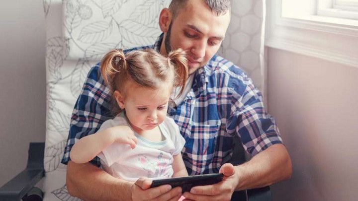 Caucasian bearded father dad holding a phone for her daughter