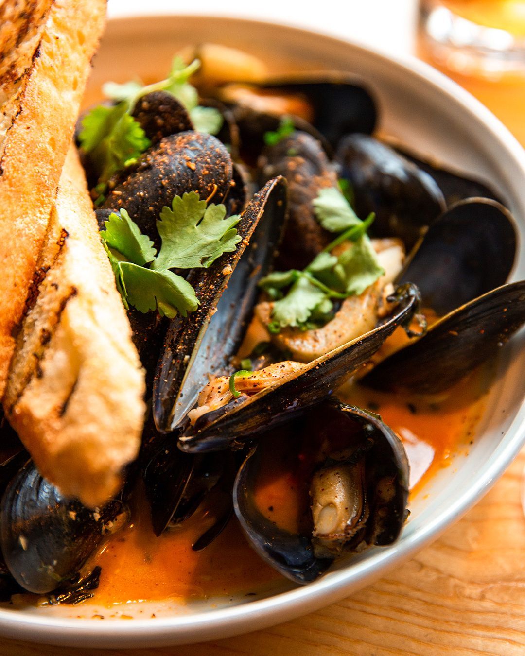 A bowl of mussels and bread on a table
