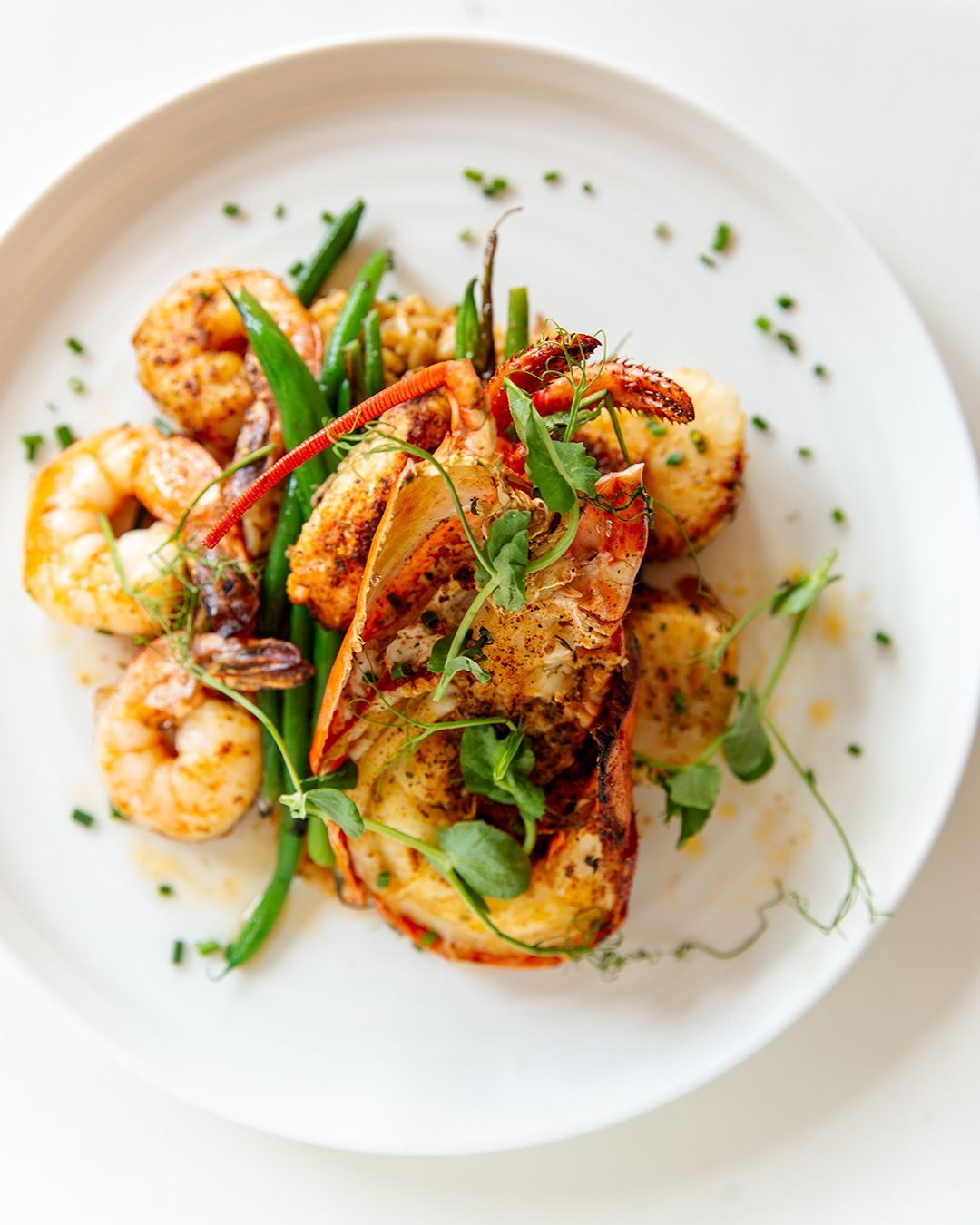 A white plate topped with shrimp and green beans on a table.