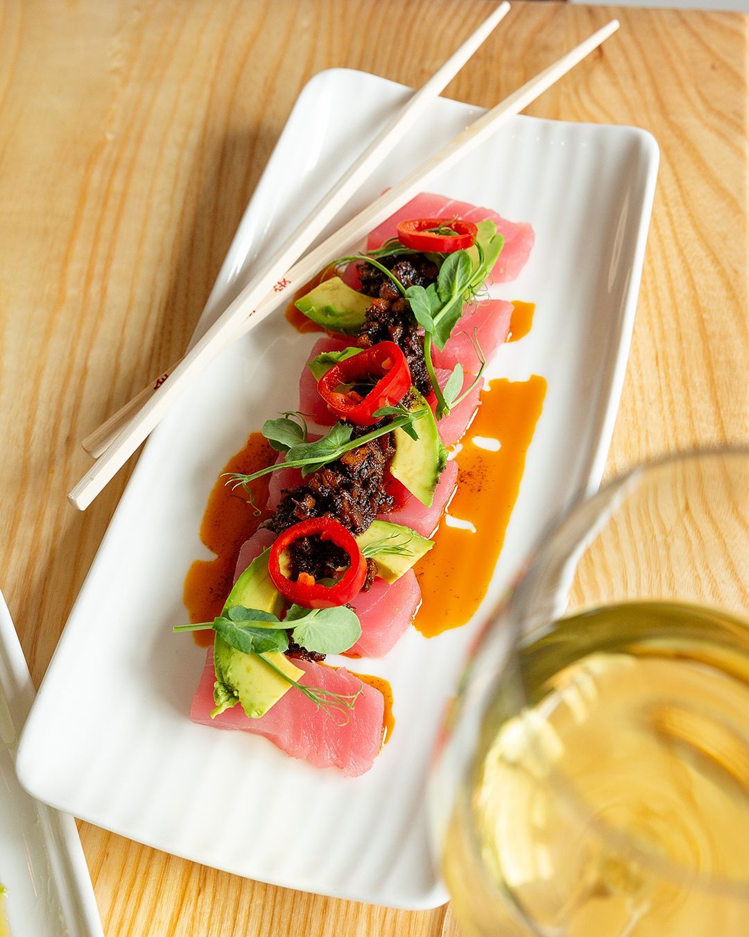 A plate of food with chopsticks and a glass of wine