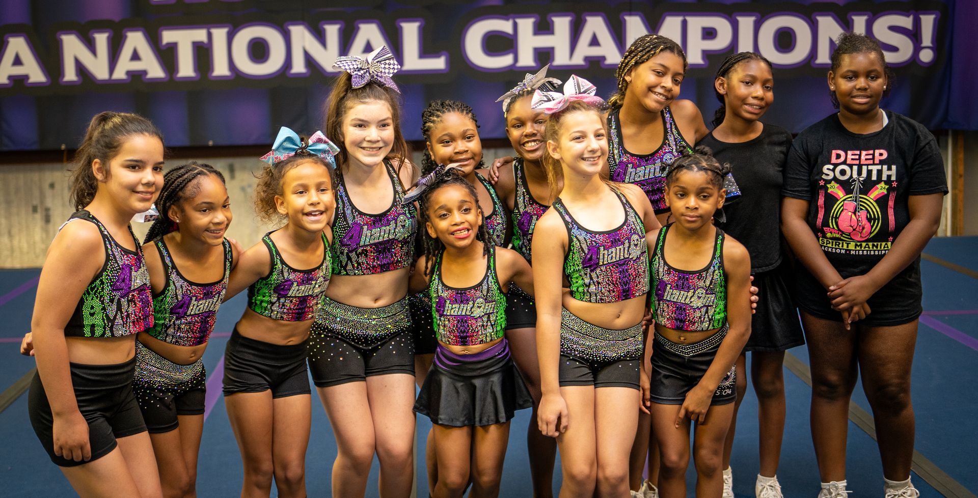 A cheerleading team in matching gray jackets holds a 