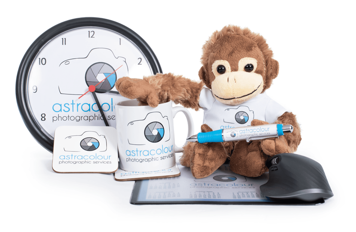 Astracol photography promotional items: clock, monkey, mug, coaster, pen, mouse, and tablet.
