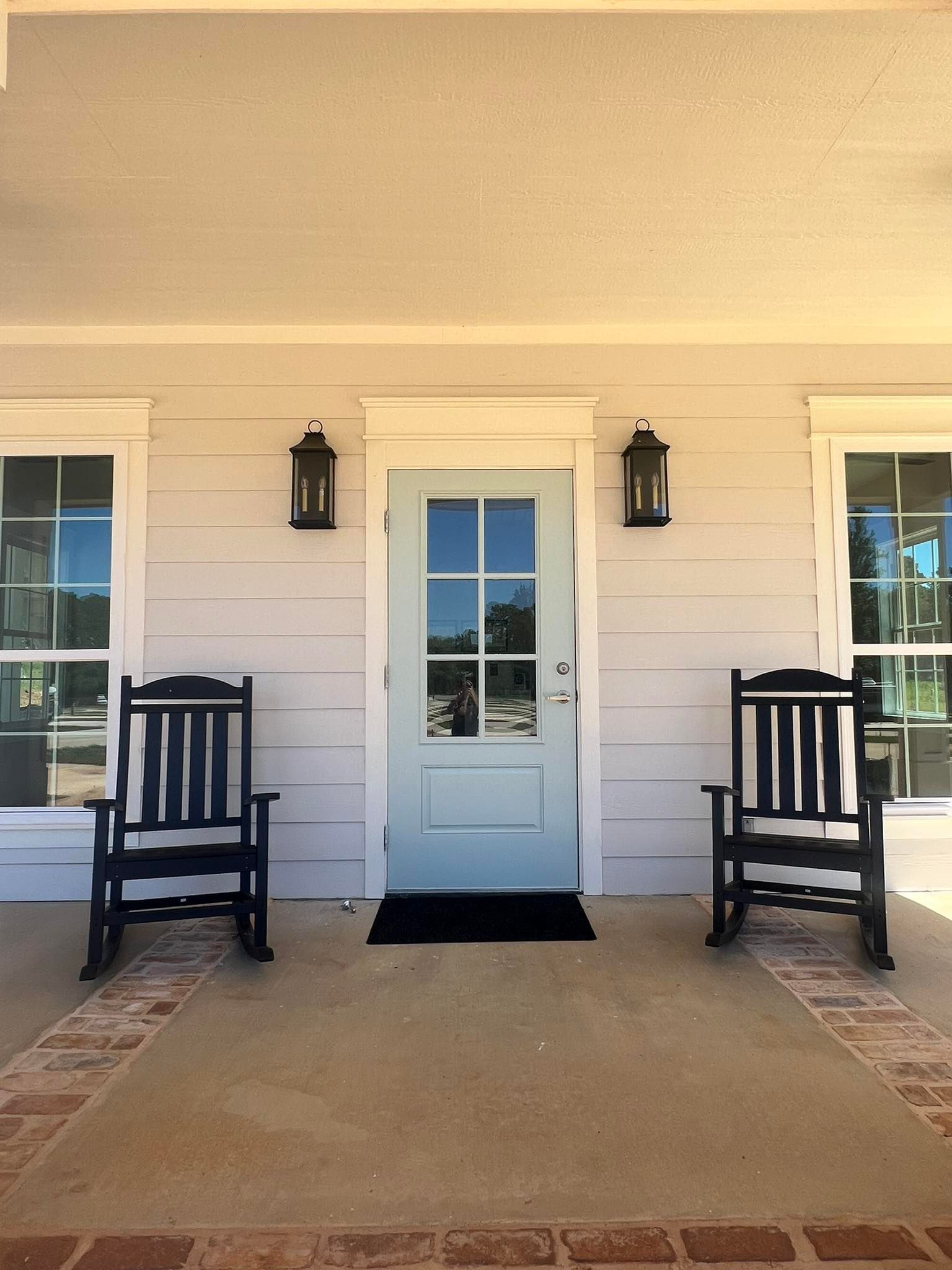 Two rocking chairs on a porch in front of a door