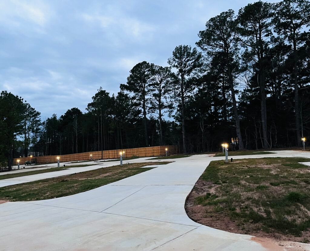 A concrete driveway going through a park with trees in the background