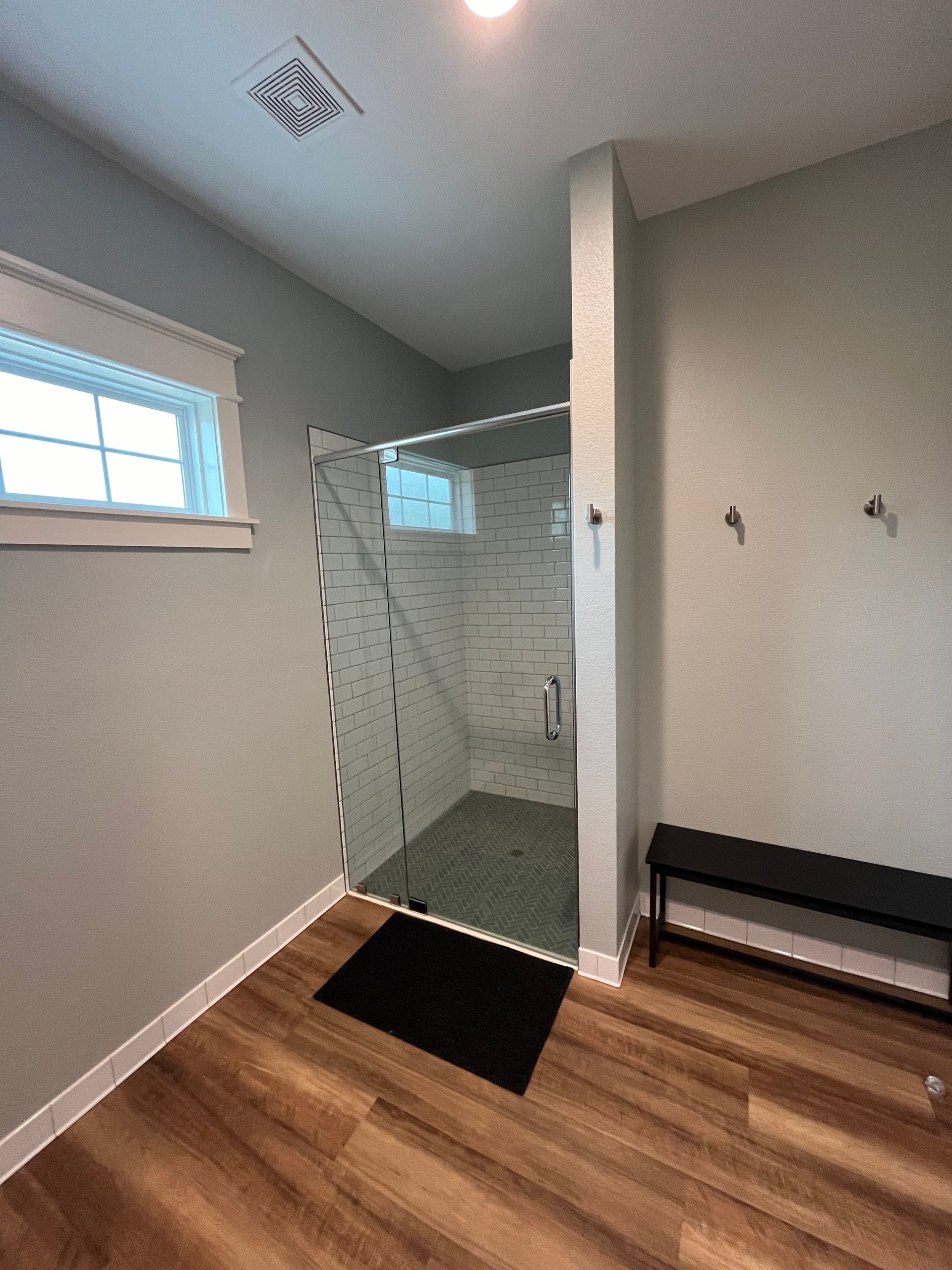 A bathroom with a walk in shower and a bench.