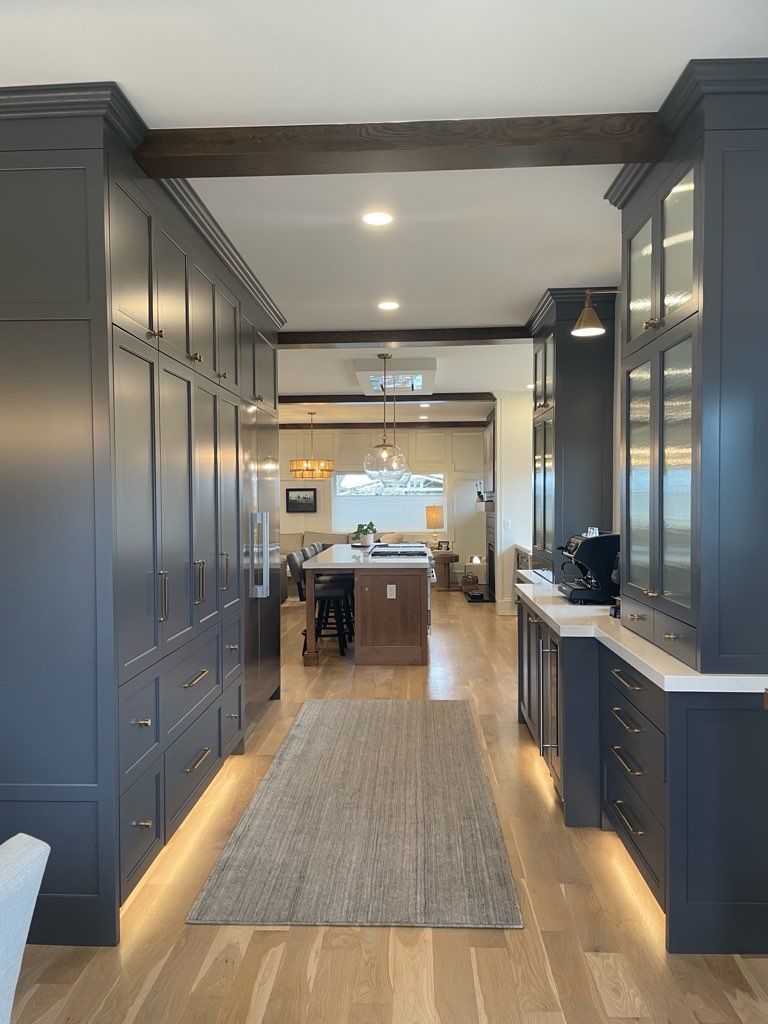 An empty kitchen with hardwood floors and white cabinets.