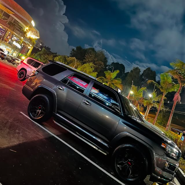 A gray suv is parked in a parking lot at night