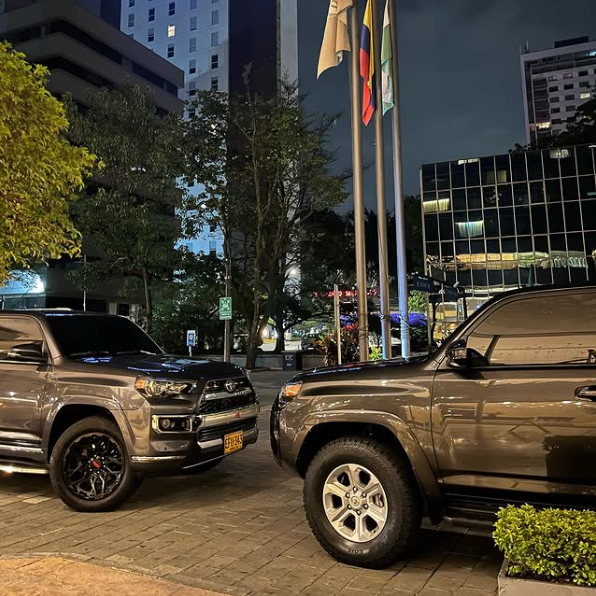 Two cars are parked next to each other in front of a building at night