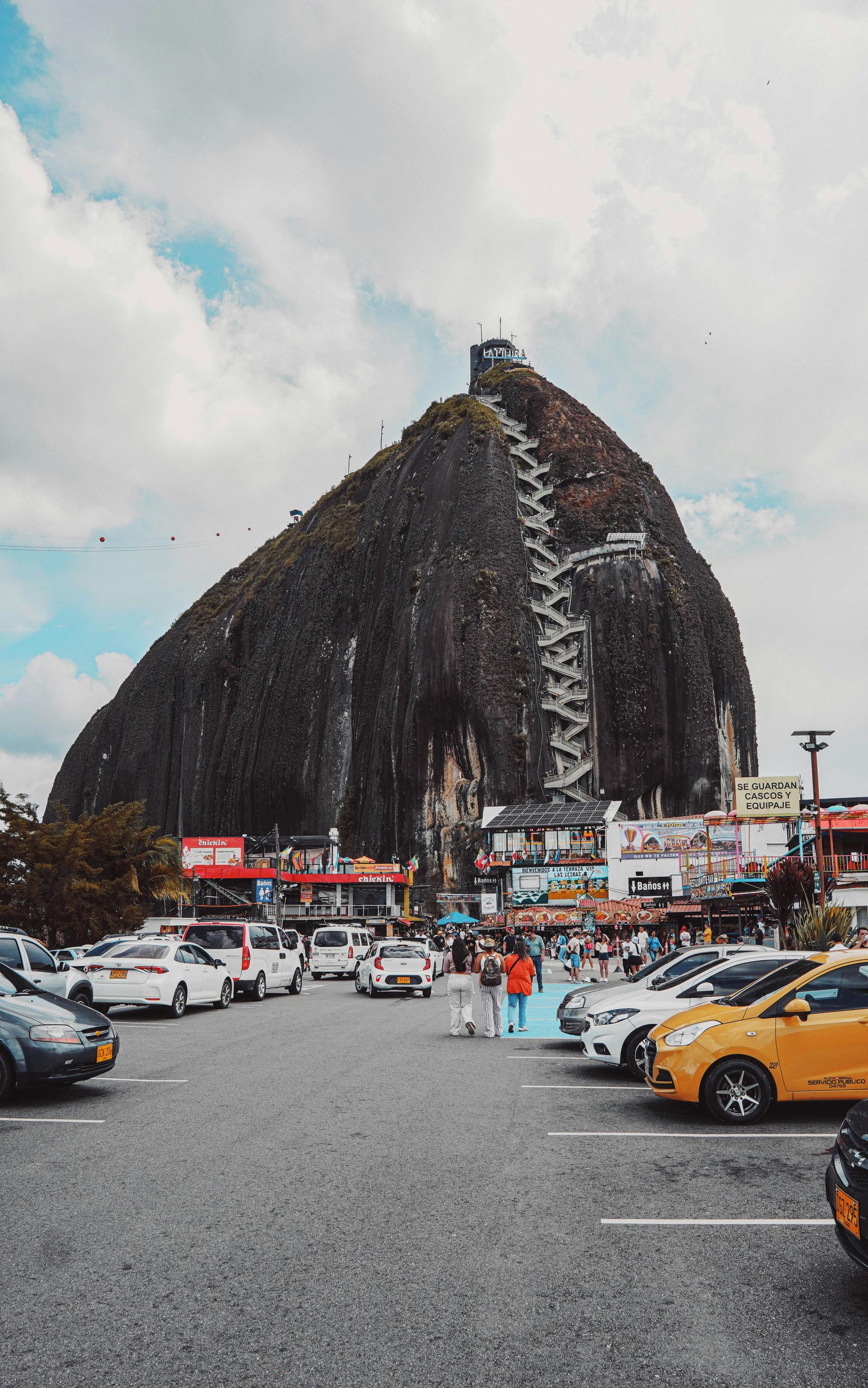 A parking lot with cars parked in front of a large rock.