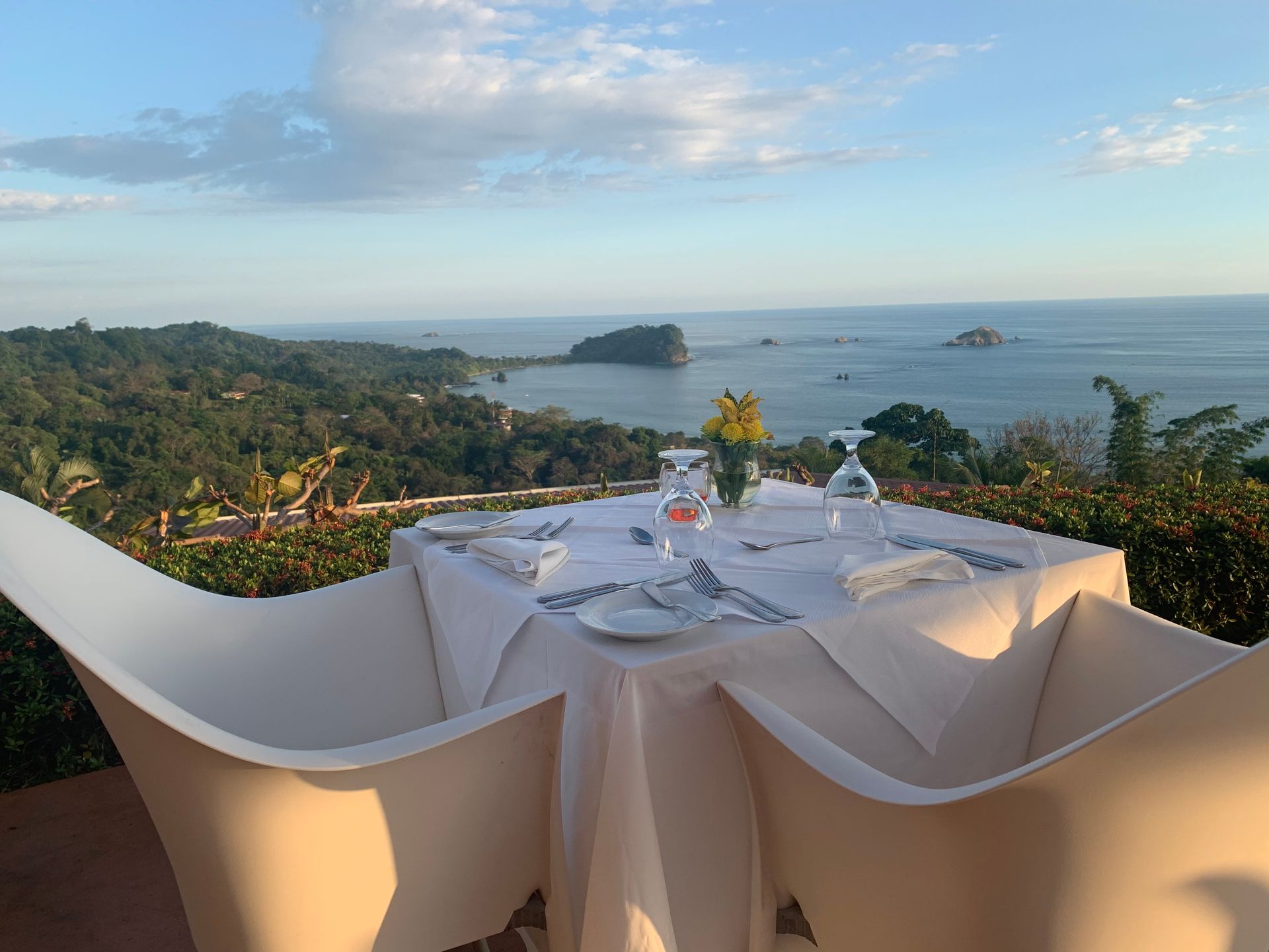 Restaurant table on a terrace overlooking a tropical bay at sunset