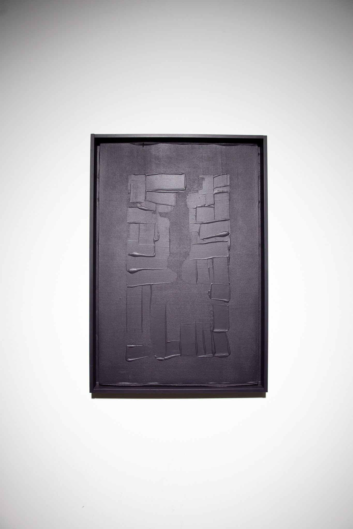 Dark rectangular artwork in a black frame, textured surface, mounted on a white wall; art by Matt Remsbecher. 