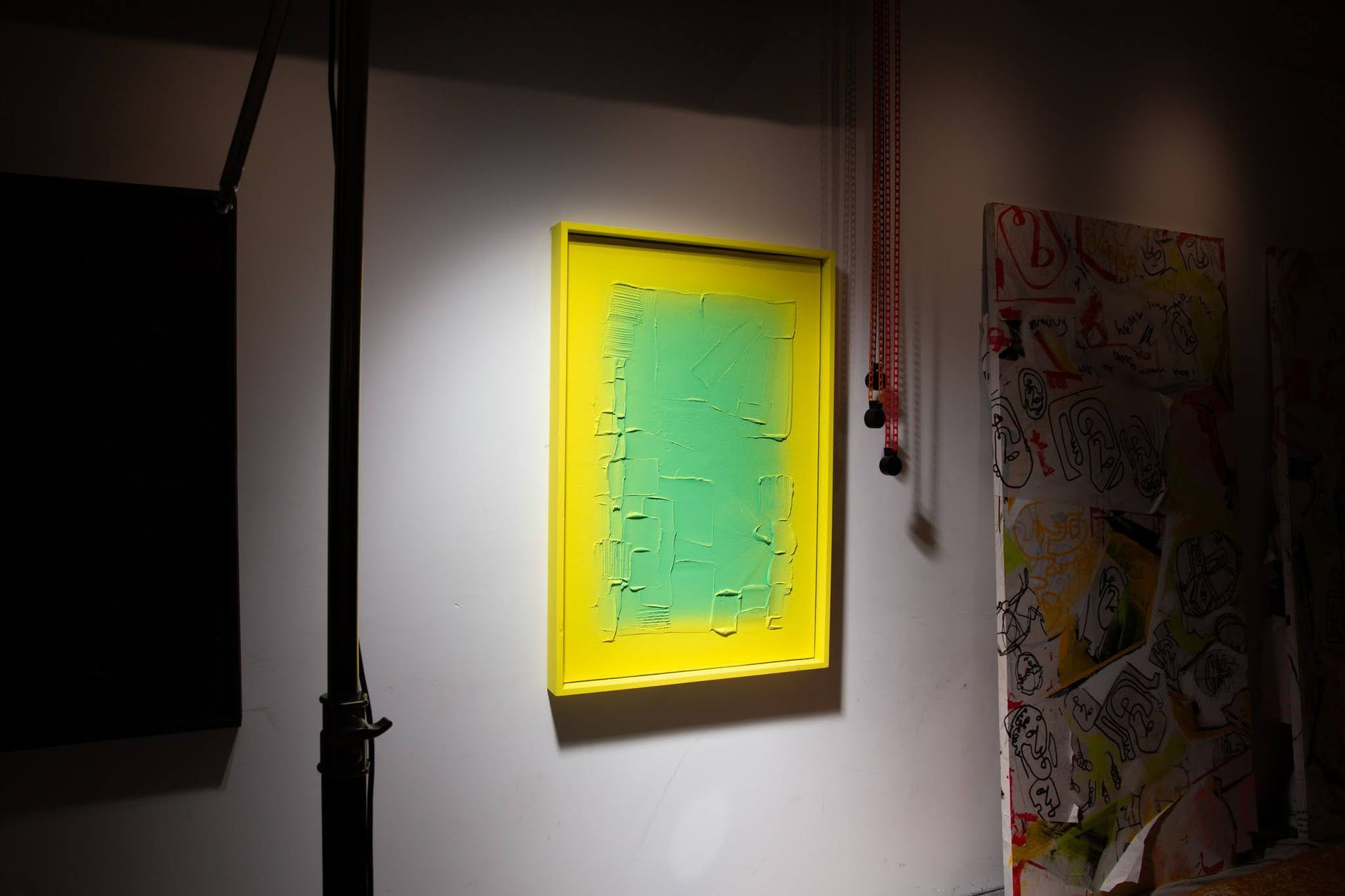 Yellow-framed artwork with green textured interior, hung on a white wall; art by Matt Remsbecher. 