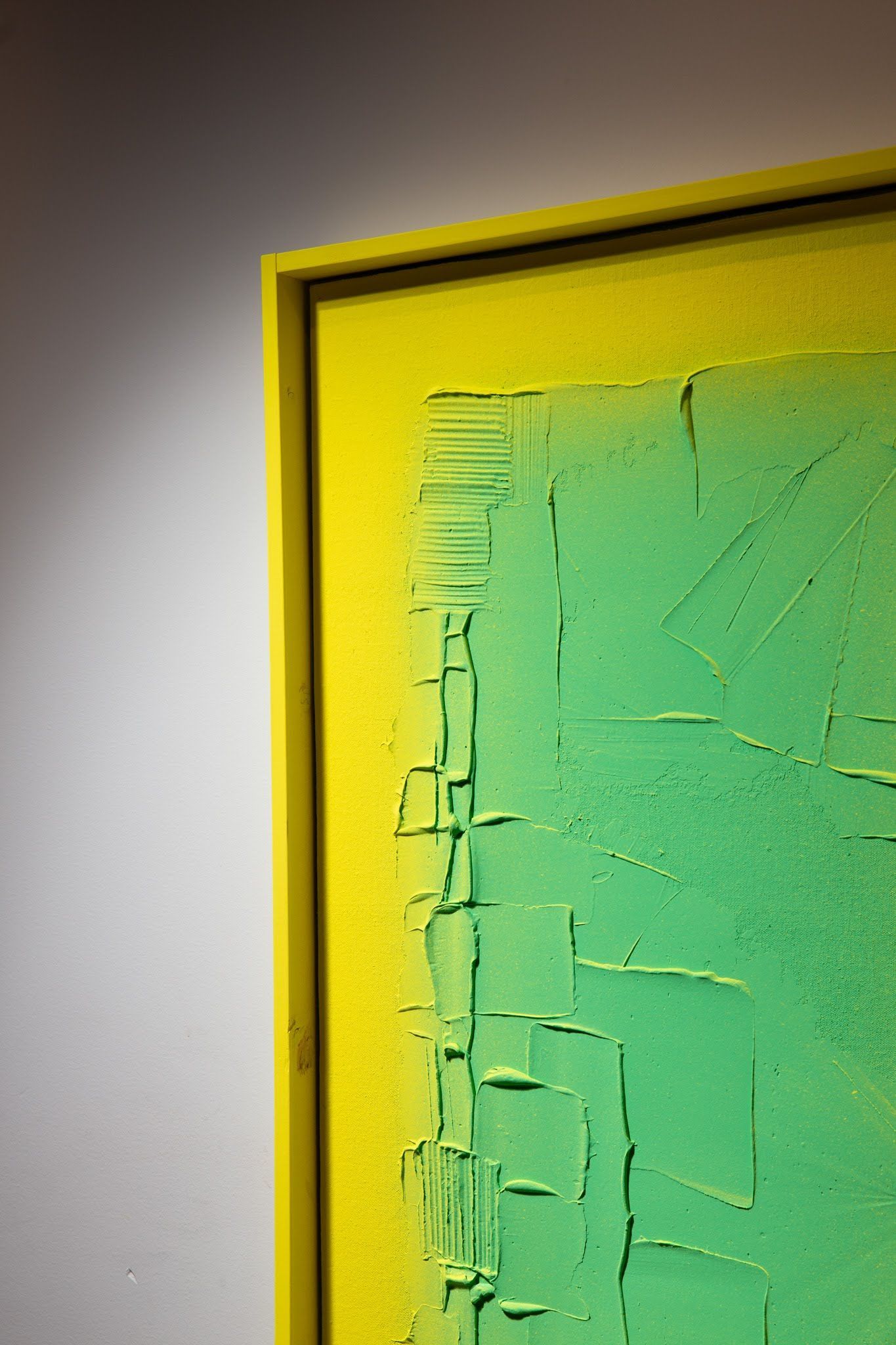 Green and yellow textured abstract painting, framed, mounted on a white wall; art by Matt Remsbecher. 