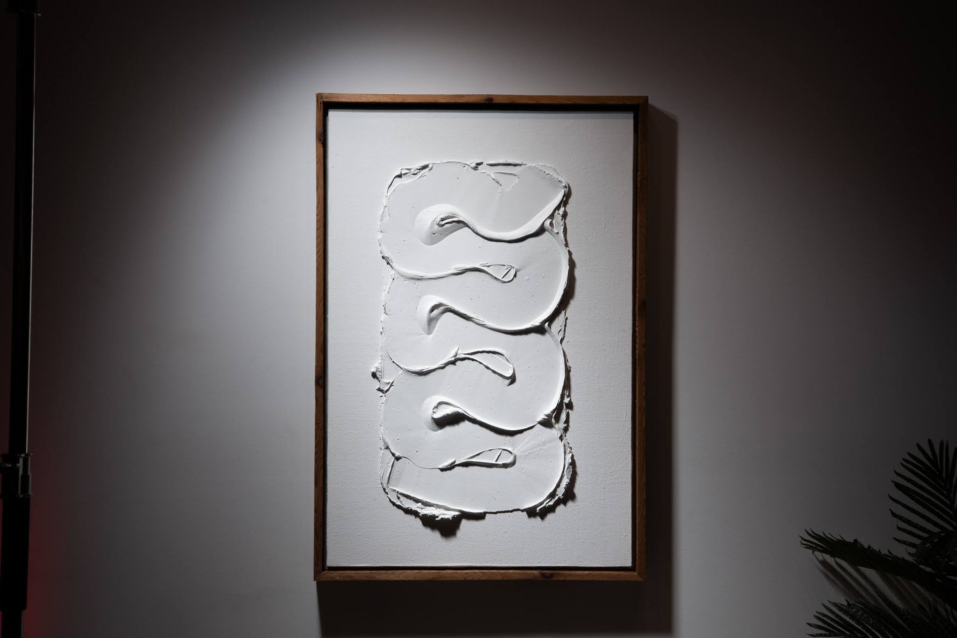 White textured abstract art within a wooden frame, mounted on a white wall; art by Matt Remsbecher. 