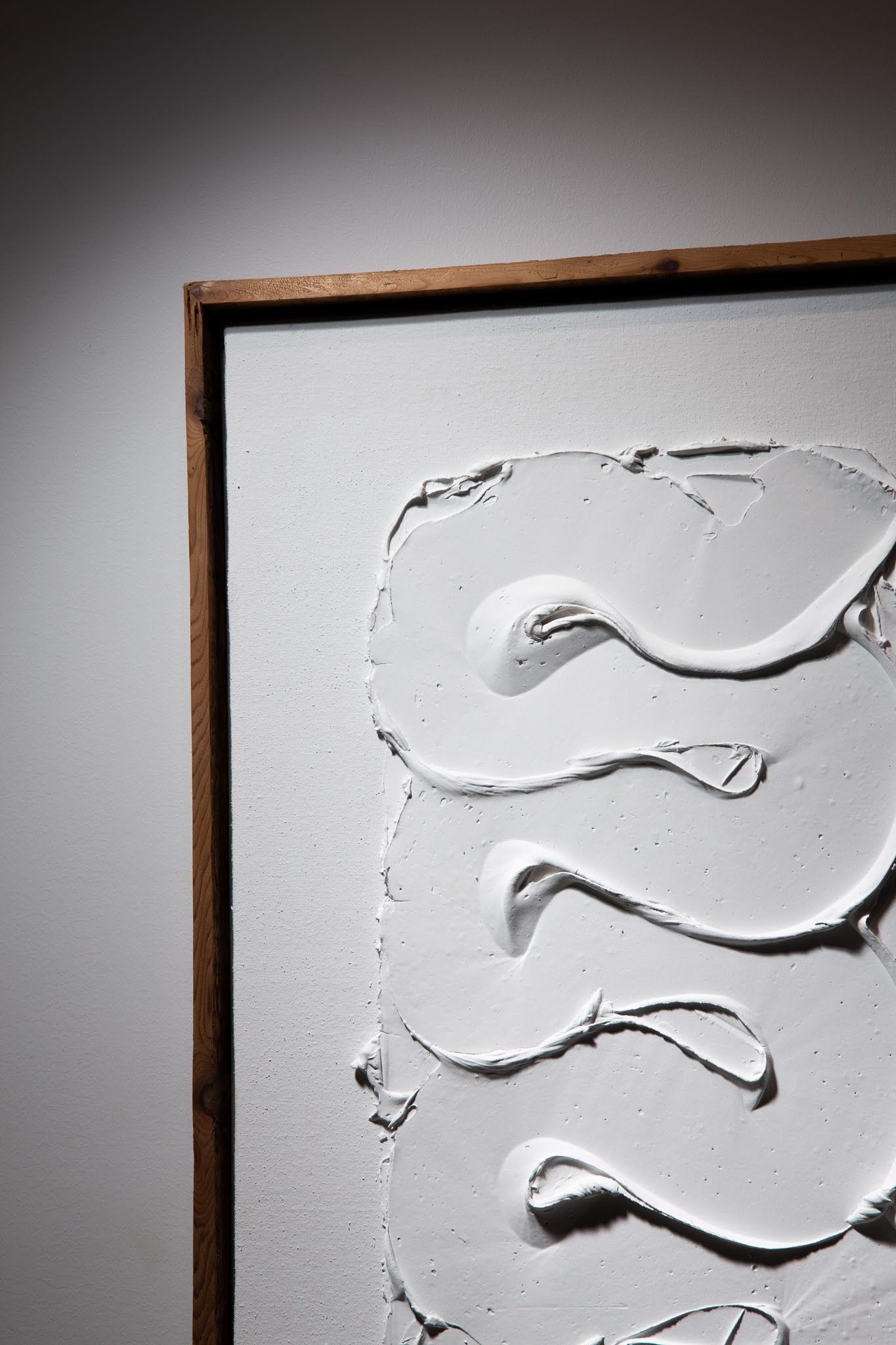 Close-up of white textured art with swirling brushstrokes in a wooden frame; art by Matt Remsbecher. 