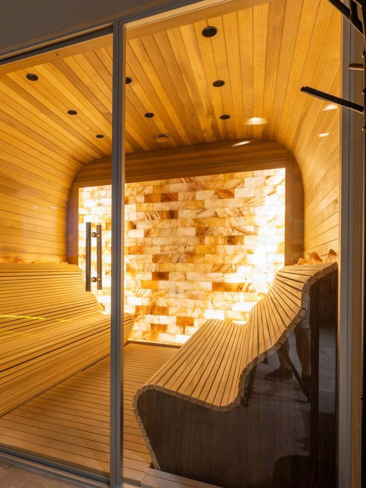 A wooden sauna with a bench and a glass door.