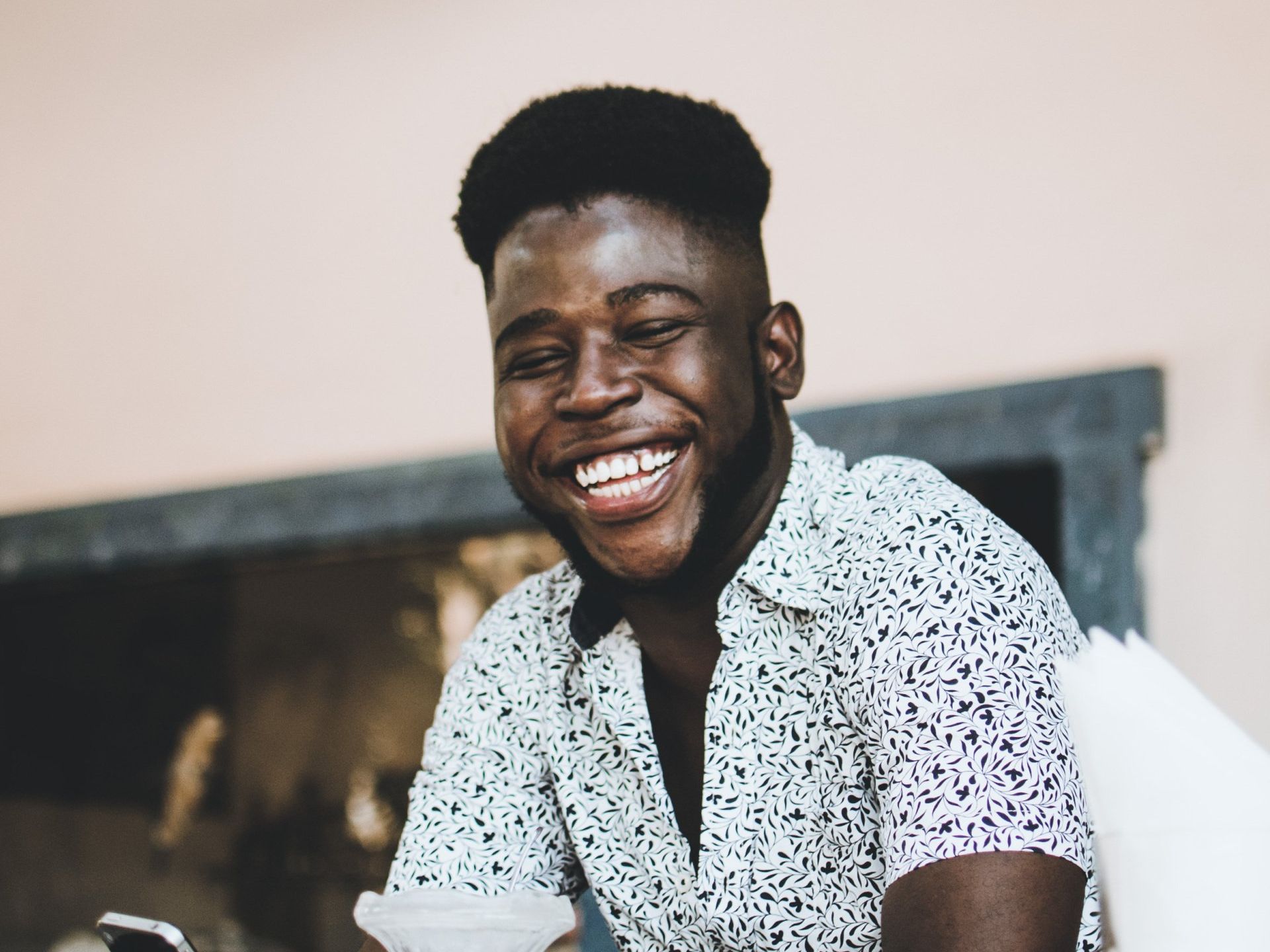 A man is smiling while looking at his cell phone.