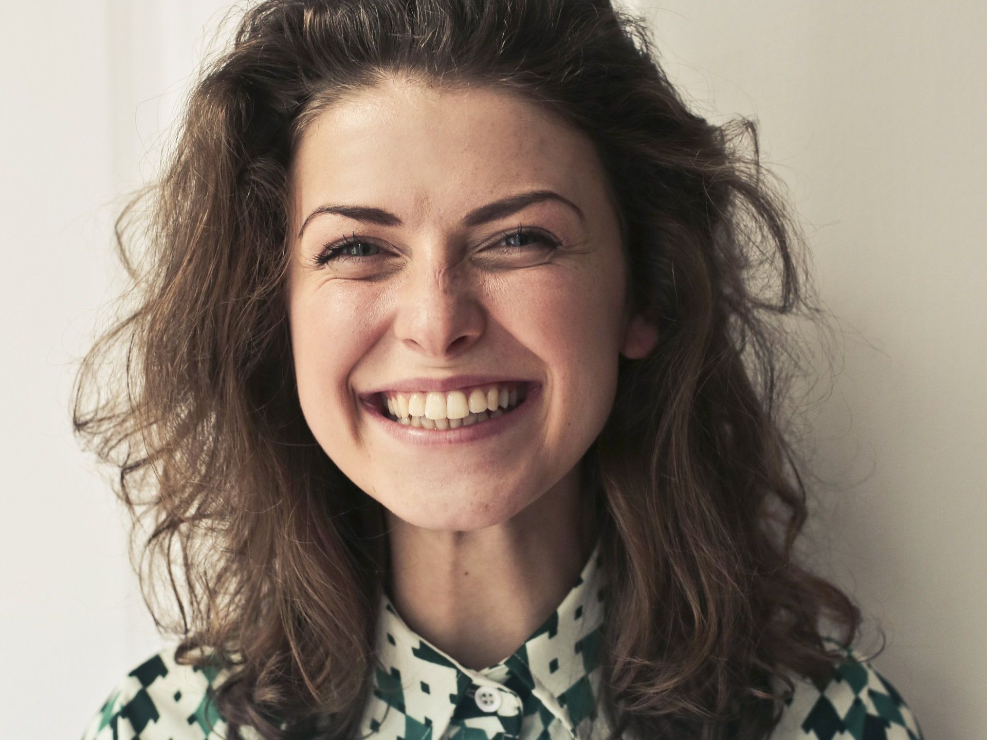 A woman with curly hair is smiling for the camera.