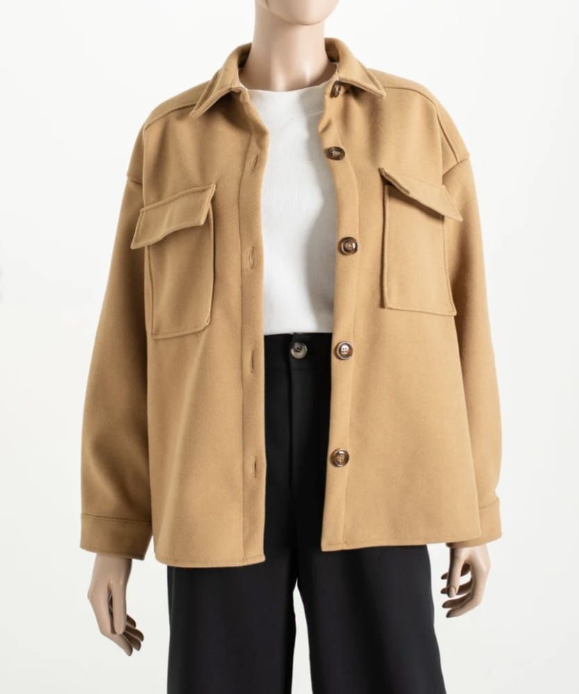 Chaqueta beige abotonada sobre una camisa blanca y pantalones negros en un maniquí.