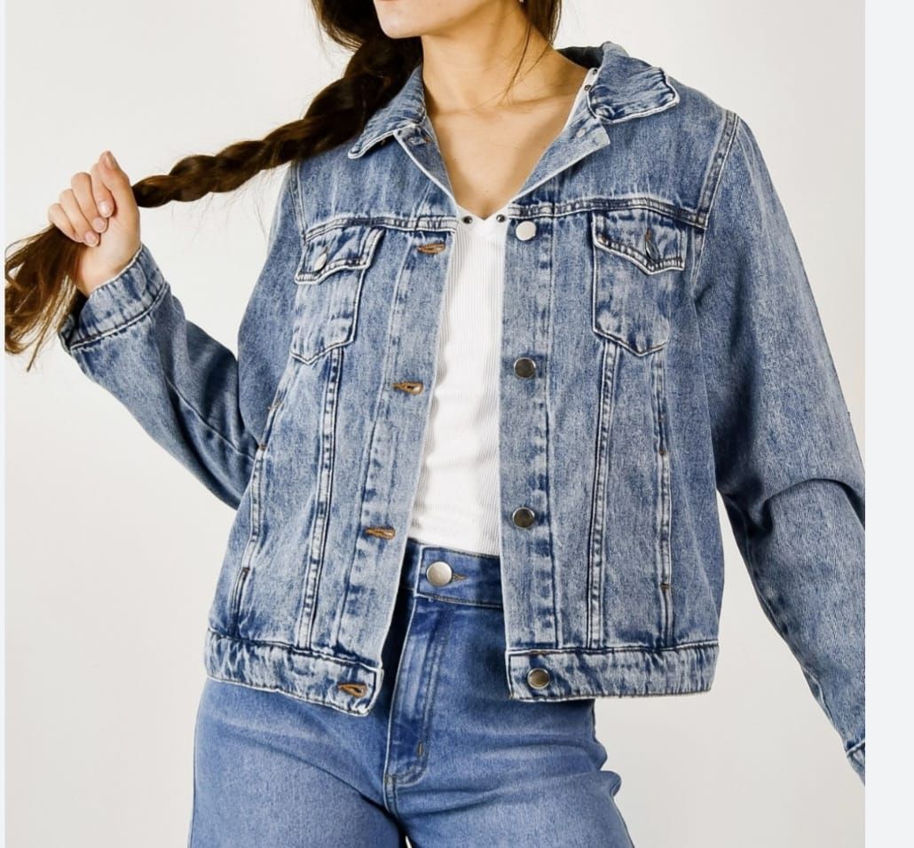 Modelo con chaqueta vaquera corta de lavado claro y vaqueros sobre una blusa blanca.