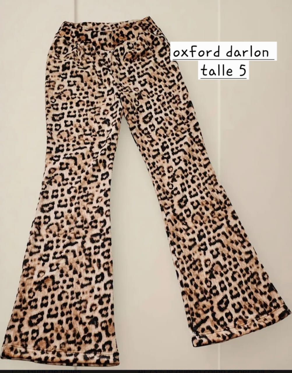 Pantalones acampanados con estampado de leopardo extendidos sobre una superficie plana, etiquetados como “oxford darlon talla 5”.