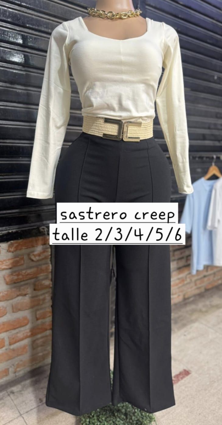Top color crema de manga larga con pantalones negros de pierna ancha en un maniquí, etiquetado como 